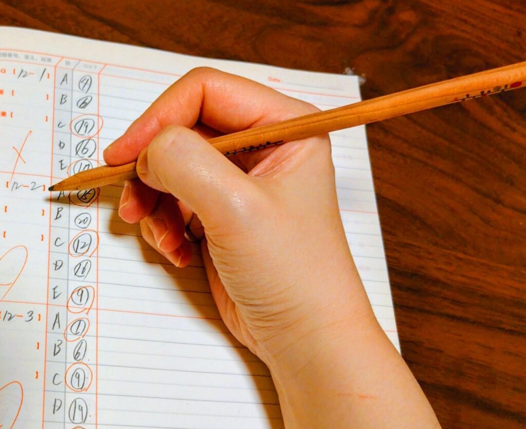 手元でノートに勉強する様子(写真AC)
