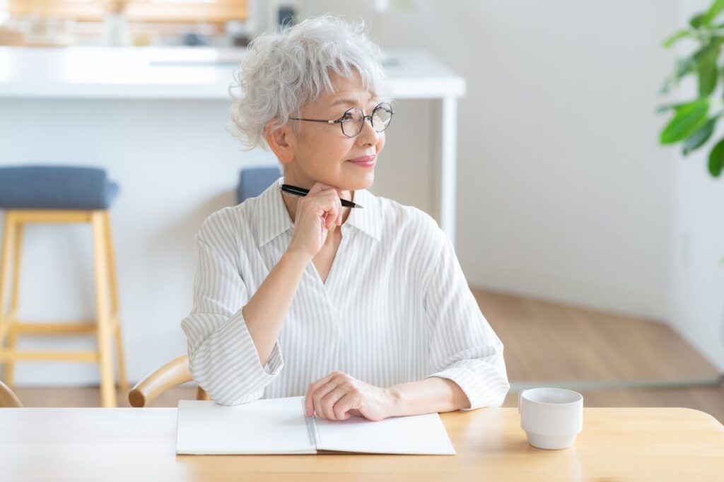 リビングで勉強をするシニア女性(写真AC)