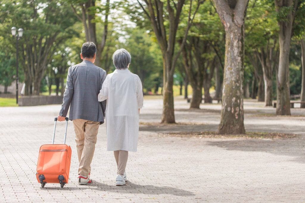 スーツケースを持って旅行するシニア夫婦（写真AC）