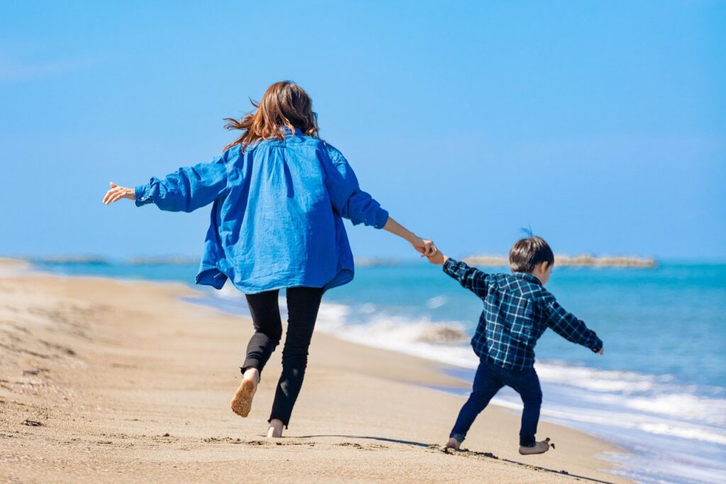 砂浜で遊ぶ母親と男の子（写真AC）